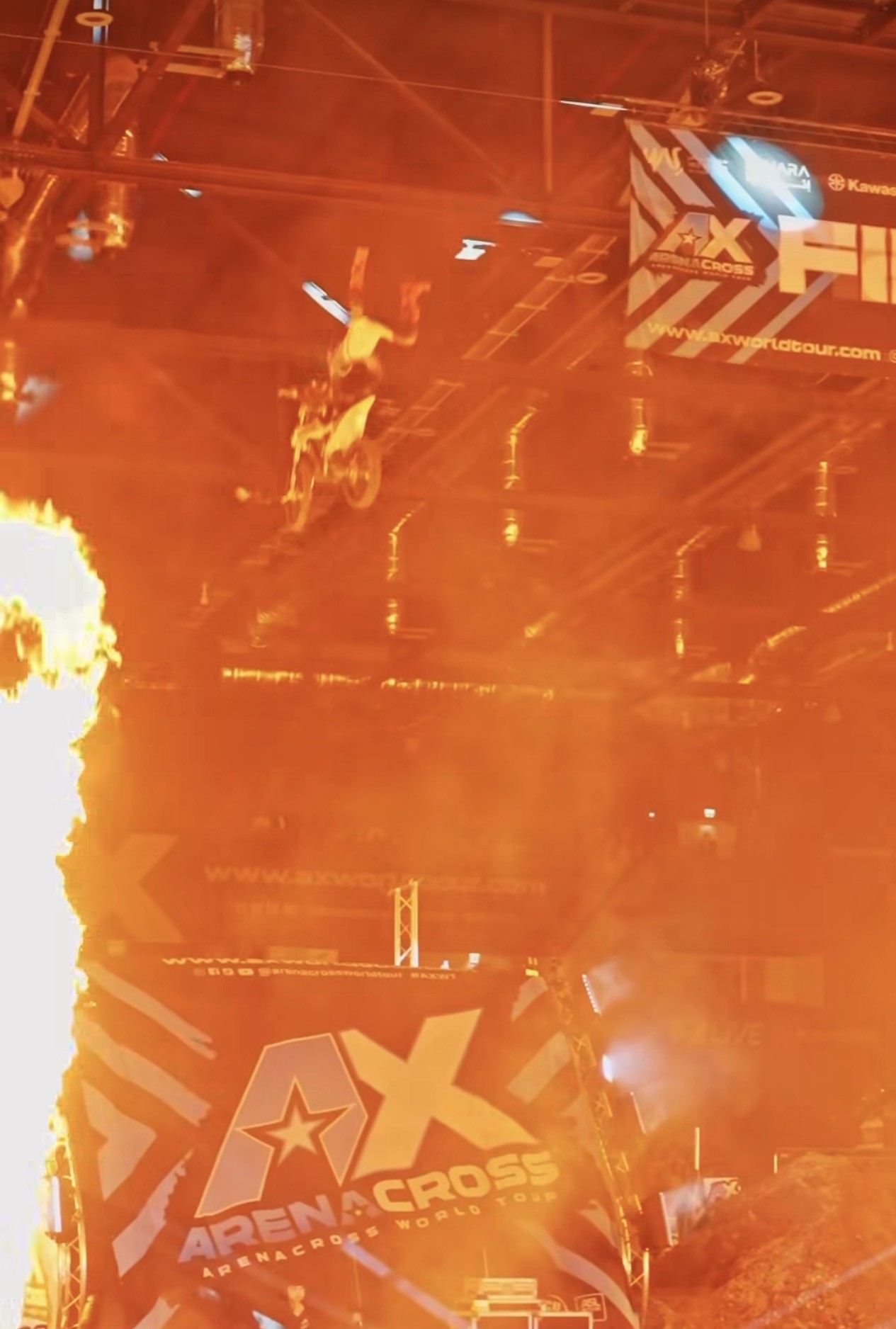 Arenacross rider jumping through the live fire show